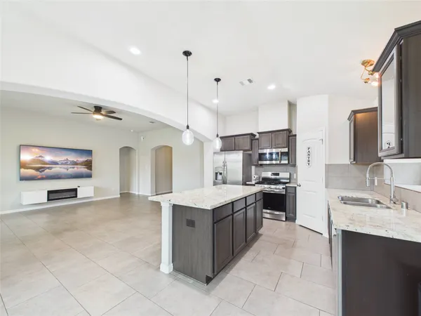 a large kitchen with stainless steel appliances lots of counter top space a sink a stove and a refrigerator