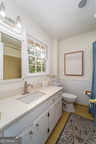 a bathroom with a double vanity sink toilet mirror and a window