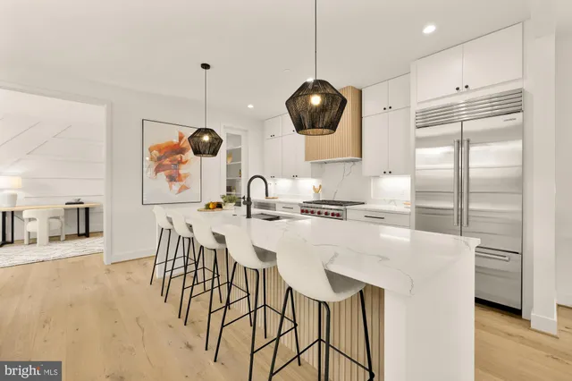 a kitchen with stainless steel appliances kitchen island granite countertop a table chairs and a refrigerator