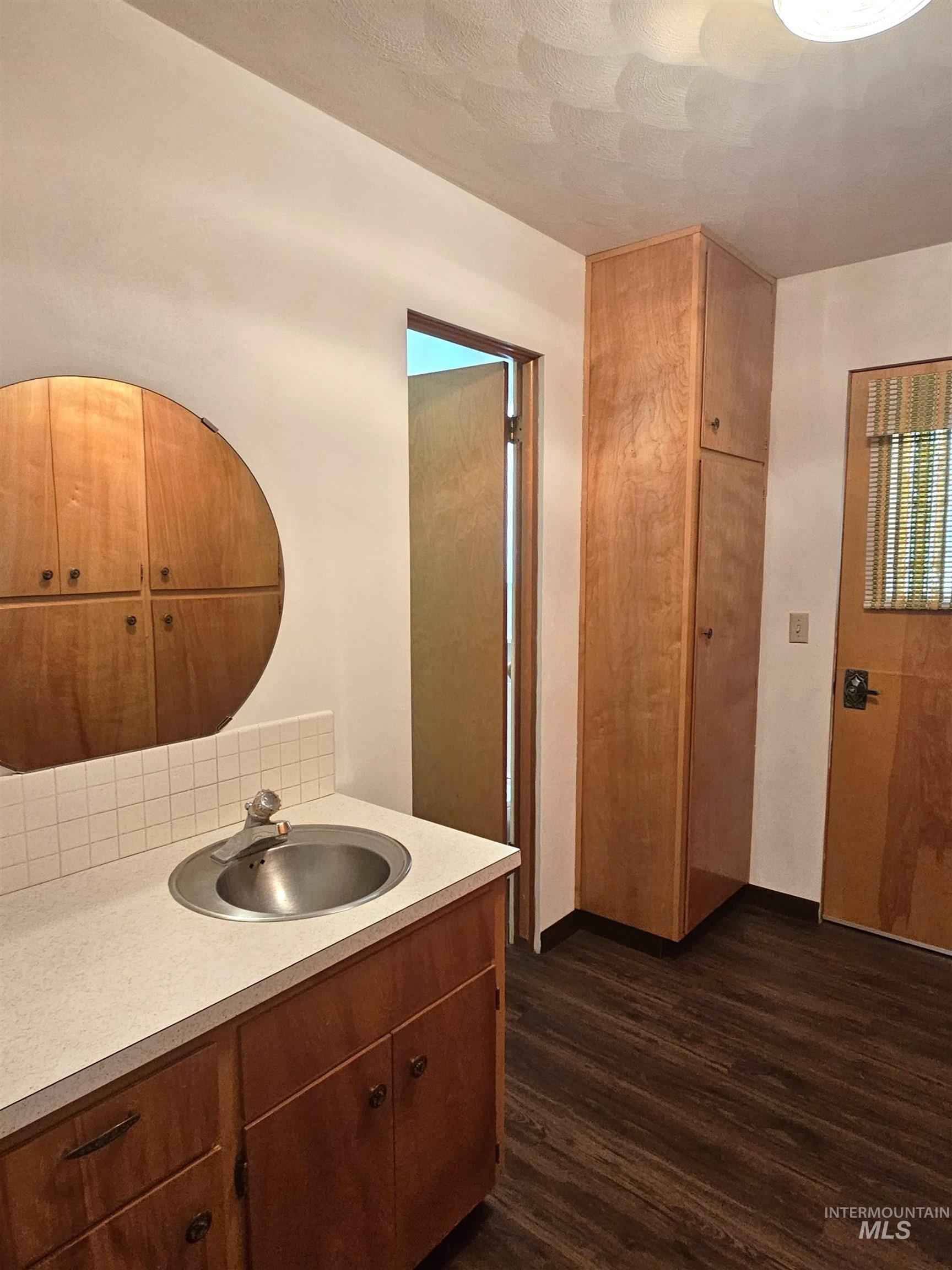 29865 Mission Creek Road Culdesac, ID 83524 - Photo 12 of 43 Back porch/Mud room featuring a vanity with circular sink, light-toned countertop, and wood-finish cabinetry with attached half bath.