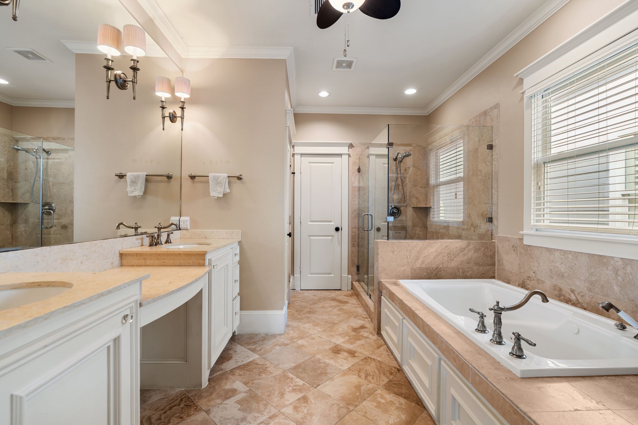 316 Aurora Street Houston, TX 77008 - Photo 16 of 31 The primary bath opens through double doors into a spacious layout featuring an extended vanity with dual sinks, dedicated knee space for a seeded vanity area, a large framed mirror with four sconces, and generous cabinetry for storage.
