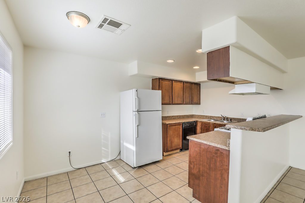 3127 North Walnut Road, Unit A Las Vegas, NV 89115 - Photo 7 of 12 A well-equipped kitchen features ample cabinetry, stone countertops, and practical tile flooring.