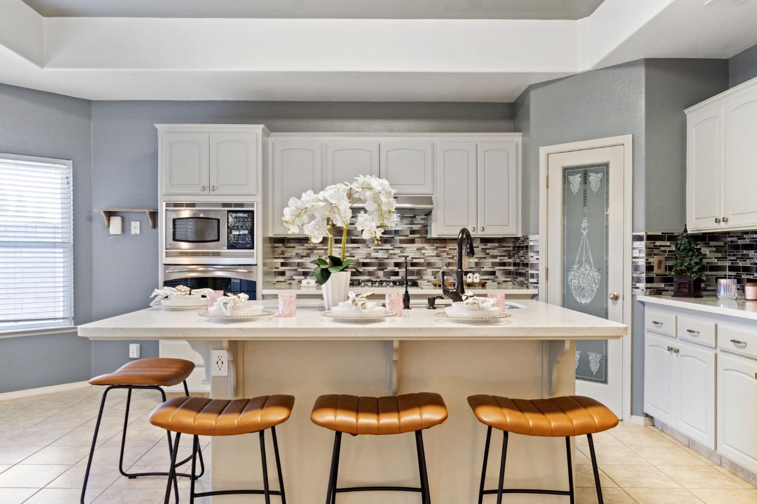 3089 Express Court Madera, CA 93637 - Photo 12 of 39 a kitchen with stainless steel appliances kitchen island granite countertop a dining table chairs and a refrigerator
