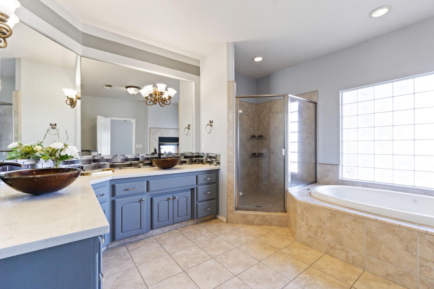 3089 Express Court Madera, CA 93637 - Photo 18 of 39 a large bathroom with a tub a sink and a large mirror