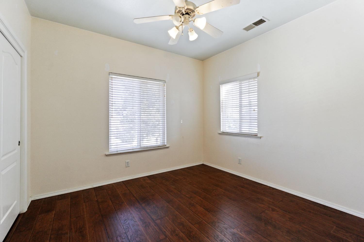 3089 Express Court Madera, CA 93637 - Photo 27 of 39 an empty room with wooden floor chandelier fan and windows
