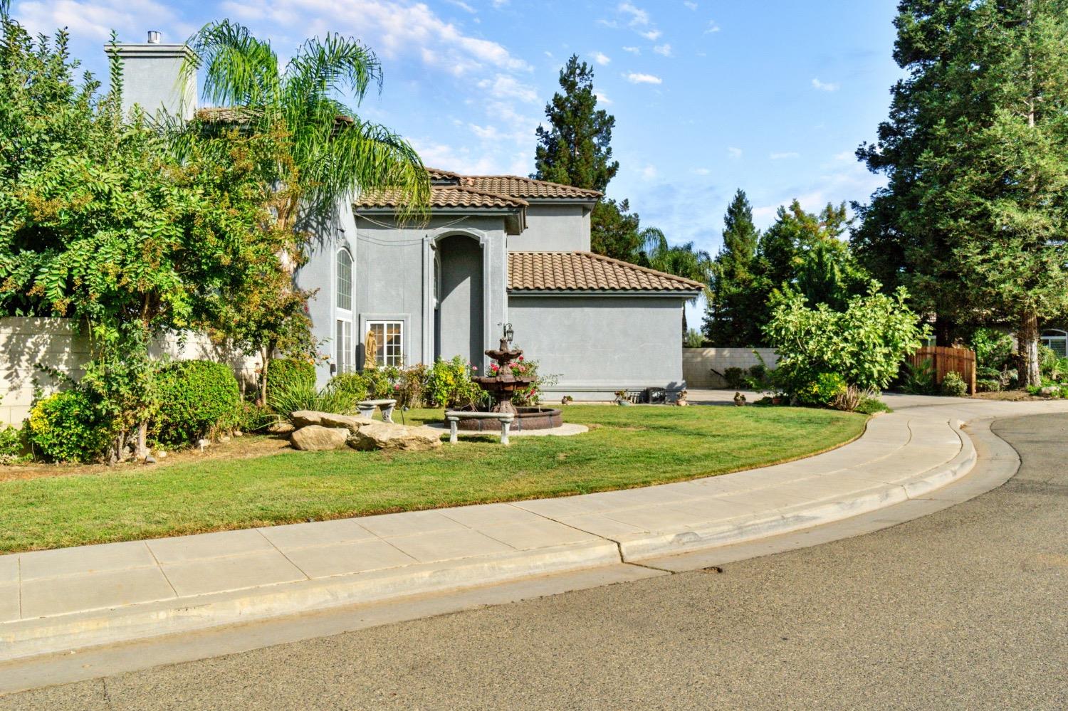 3089 Express Court Madera, CA 93637 - Photo 33 of 39 a front view of a house with a garden and trees
