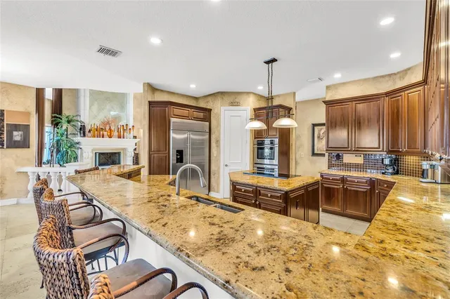 a kitchen with stainless steel appliances granite countertop a stove a refrigerator a oven a sink with island cabinets and wooden floor