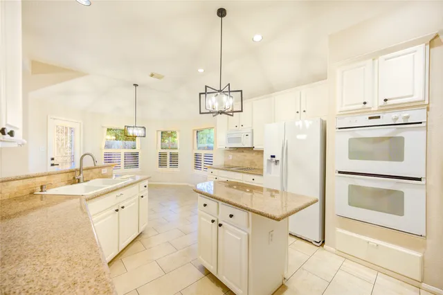 a kitchen with granite countertop a stove and white cabinets