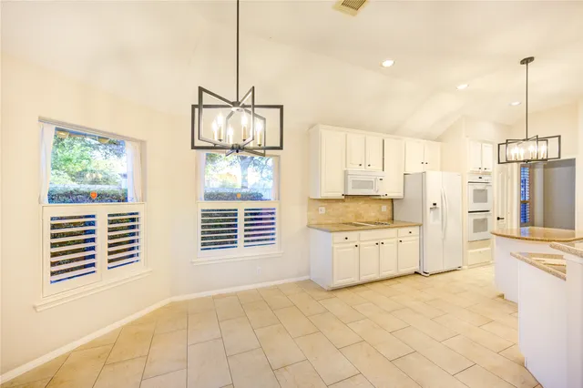 a kitchen with stainless steel appliances granite countertop a refrigerator and white cabinets