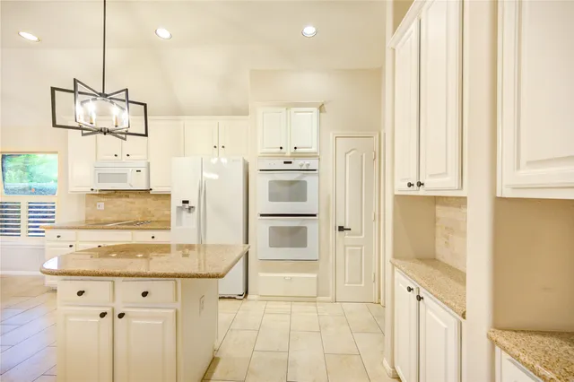 a kitchen with white cabinets and window