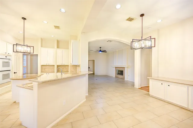 a view of a kitchen with kitchen island a sink stainless steel appliances wooden floor and cabinets