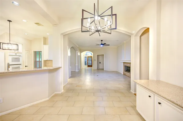 a view of a livingroom with a chandelier and kitchen view