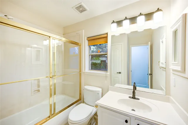 a view of a big room with wooden floor a ceiling fan and windows