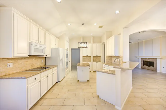 a large white kitchen with stainless steel appliances kitchen island granite countertop a sink and cabinets