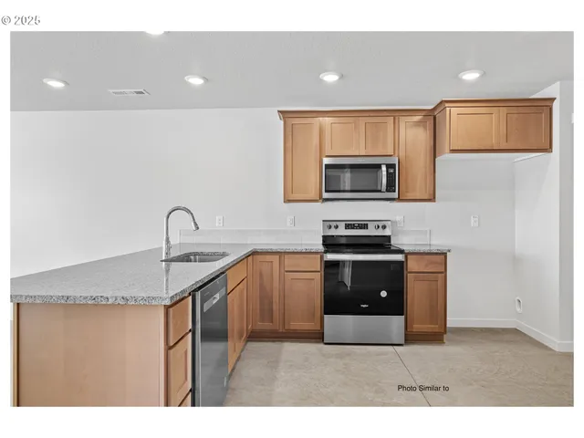 a kitchen with stainless steel appliances granite countertop a stove a sink and a microwave