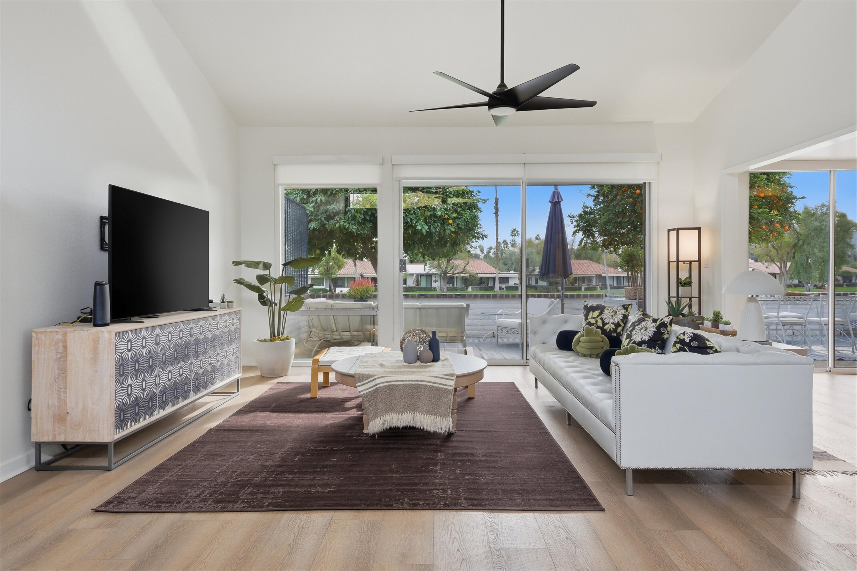 a living room with furniture a large window and a flat screen tv