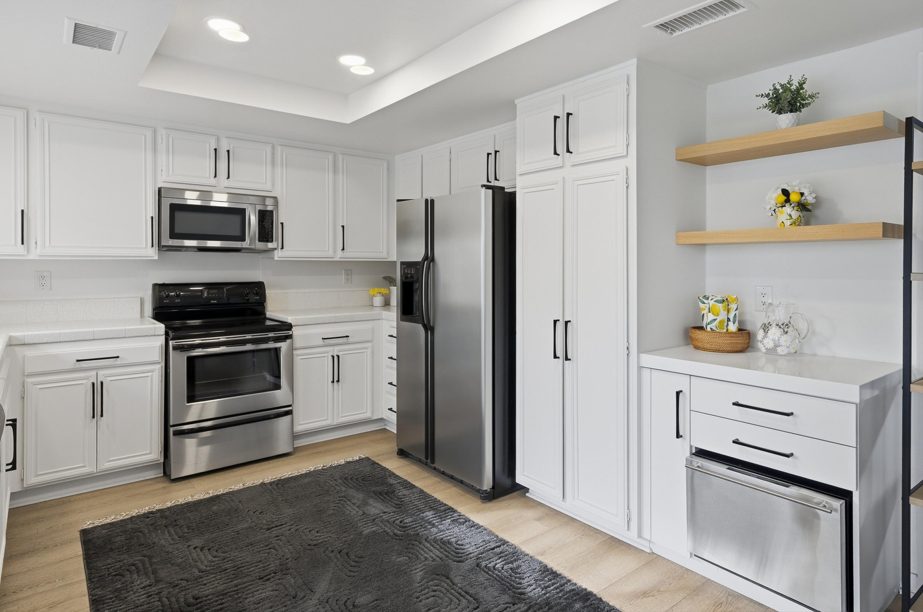 23 Leon Way Rancho Mirage, CA 92270 - Photo 12 of 32 a kitchen with white cabinets and stainless steel appliances