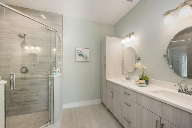 a bathroom with a double vanity sink mirror and shower