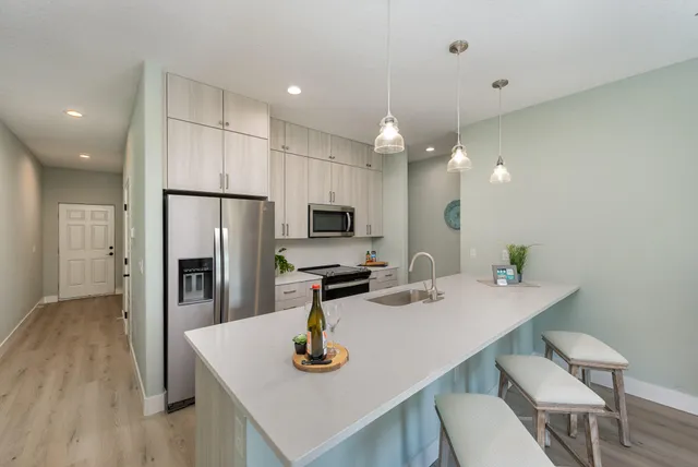 a kitchen with stainless steel appliances kitchen island granite countertop a sink a refrigerator and a stove