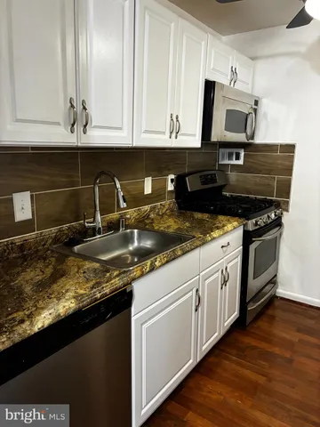 a kitchen with granite countertop a sink a stove and cabinets