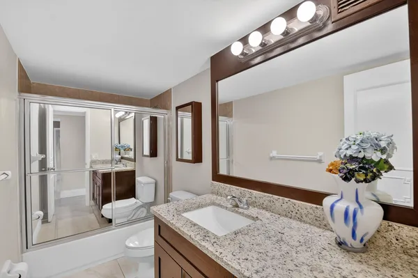 a bathroom with a granite countertop sink a large mirror and a shower