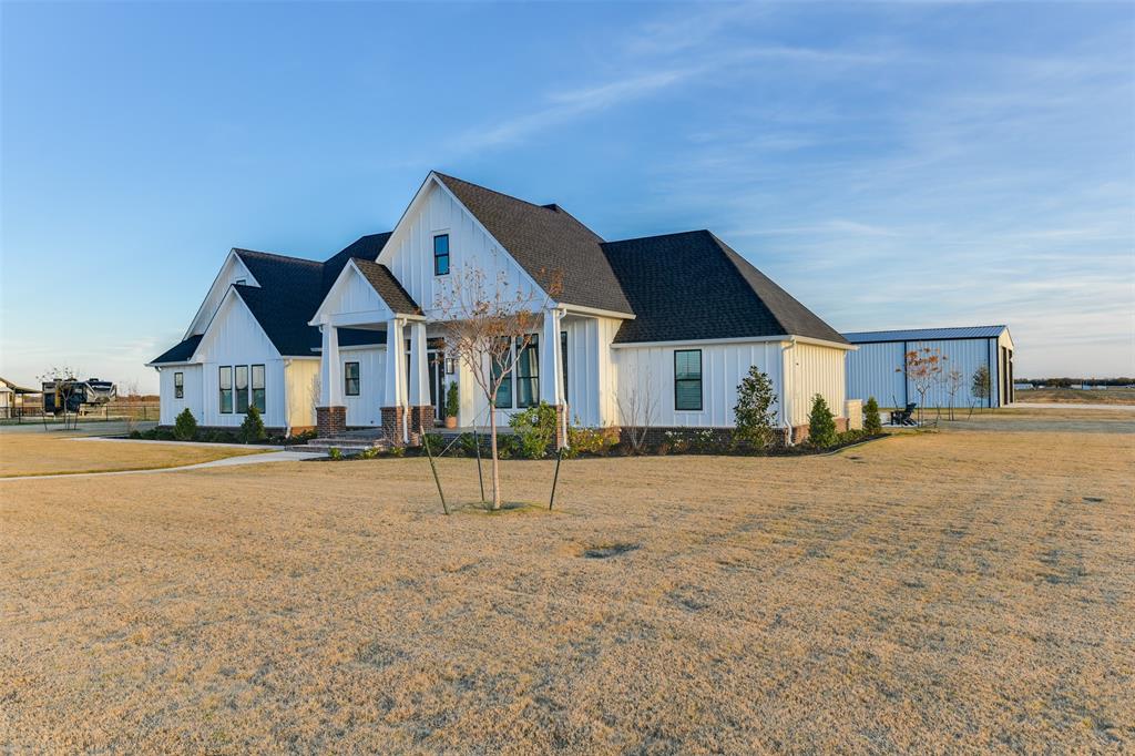 Modern farmhouse featuring a front lawn, board and batten siding, and roof with shingles