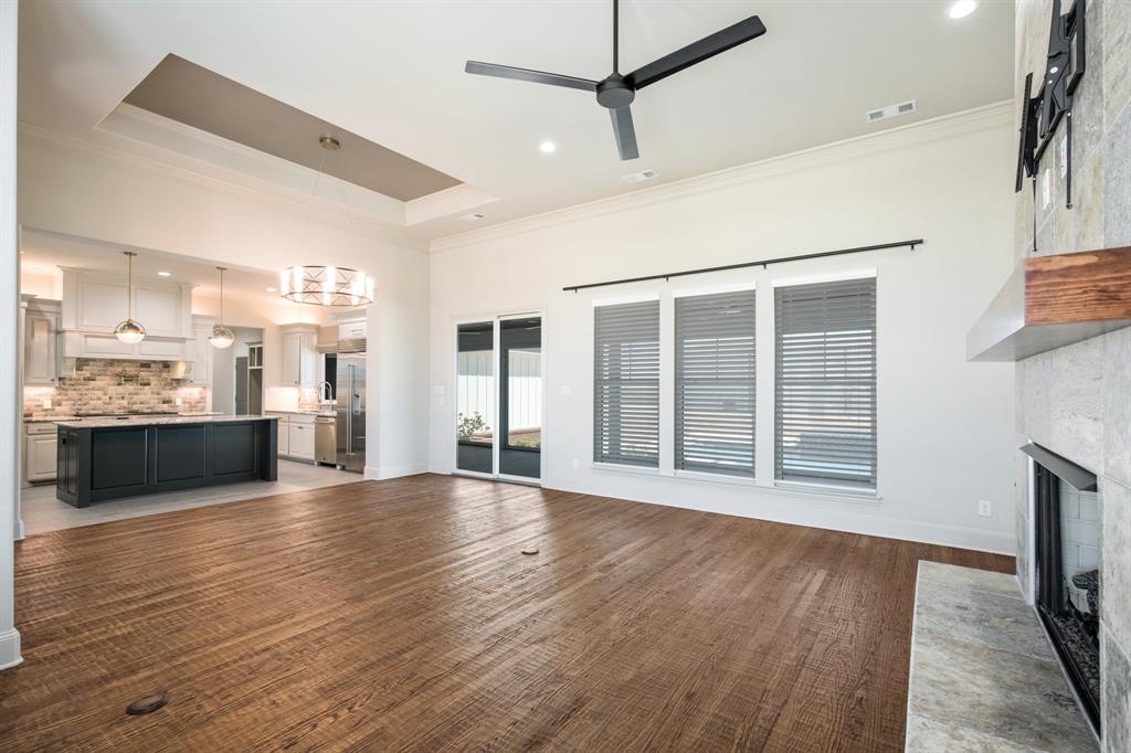 470 Forreston Road Waxahachie, TX 75165 - Photo 23 of 38 Unfurnished living room featuring visible vents, a fireplace with flush hearth, ceiling fan with notable chandelier, crown molding, and a raised ceiling