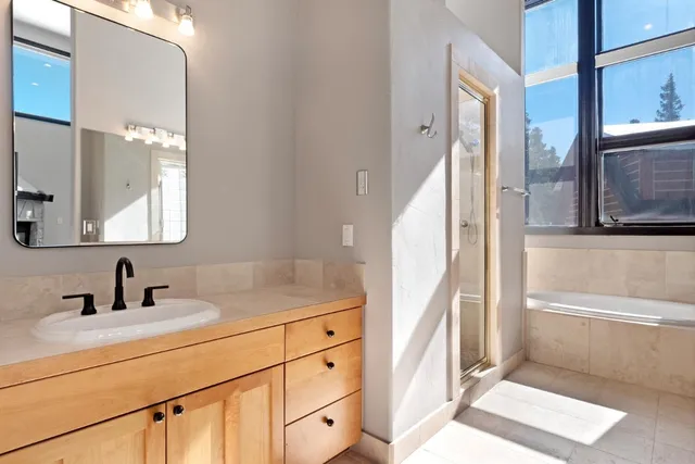 a bathroom with a double vanity sink and mirror with bathtub