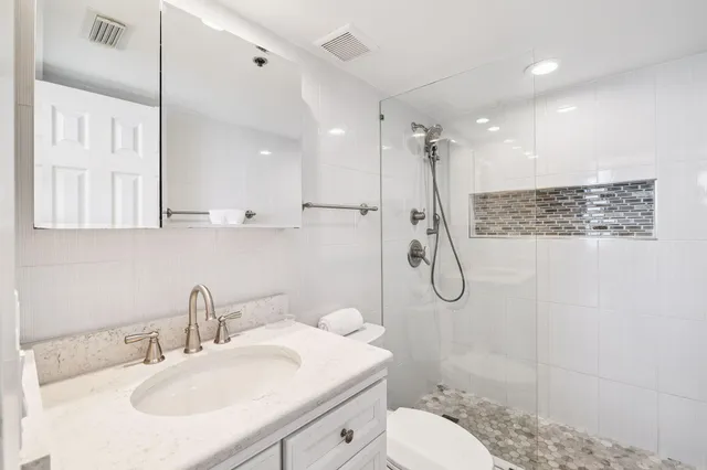 a bathroom with a granite countertop sink a toilet and shower