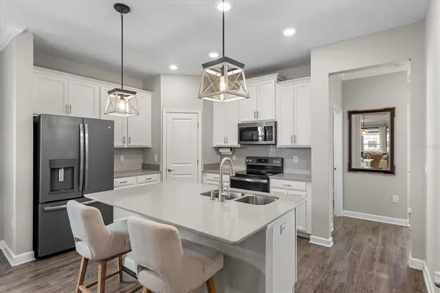 a kitchen with stainless steel appliances a dining table chairs refrigerator and microwave