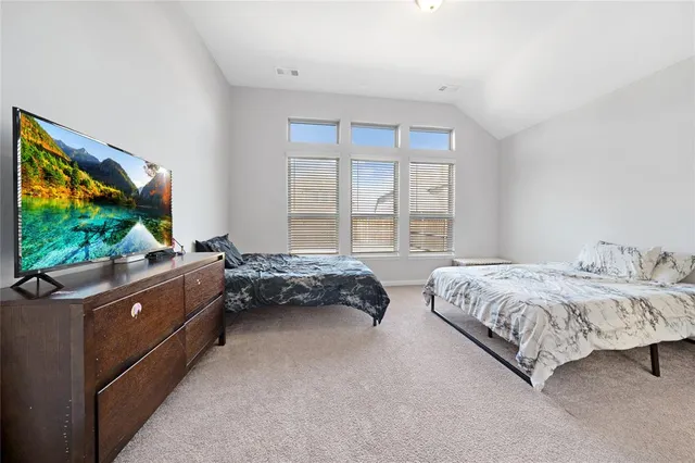 a spacious bedroom with a bed and a flat screen tv