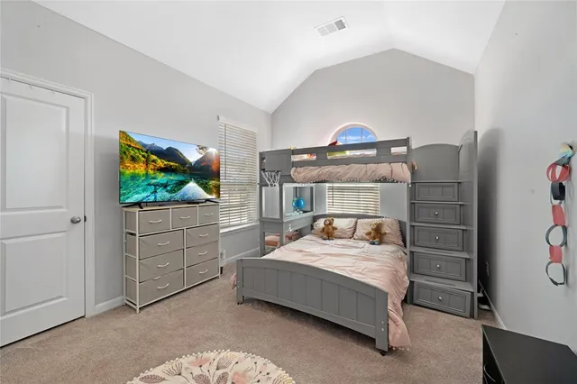 a bedroom with a bed and a flat tv screen on dresser