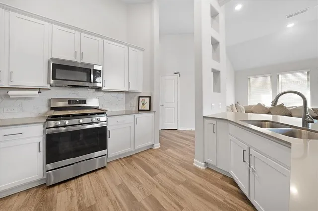 a kitchen with stainless steel appliances granite countertop a stove a sink and a microwave