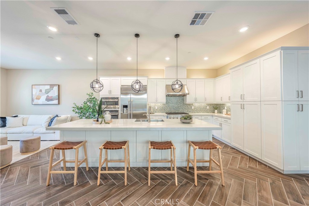 a kitchen with kitchen island stainless steel appliances a table chairs sink and wooden floor