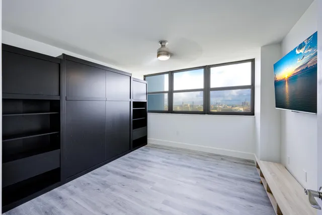 a view of empty room with wooden floor and fan
