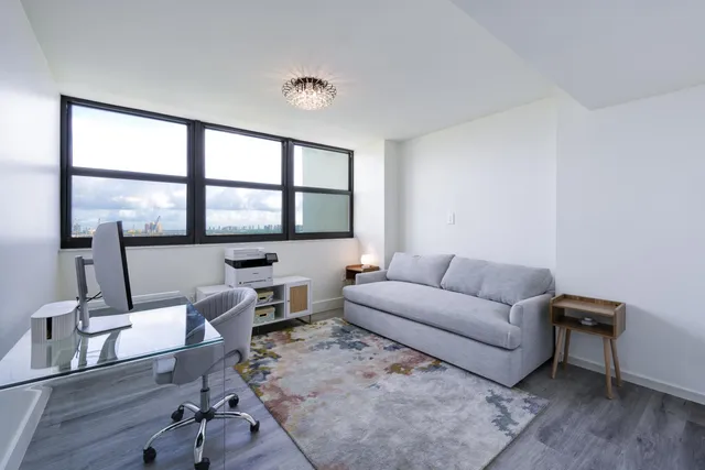 a living room with furniture a flat screen tv and a large window