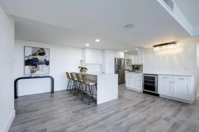a kitchen with stainless steel appliances kitchen island wooden floors and white cabinets
