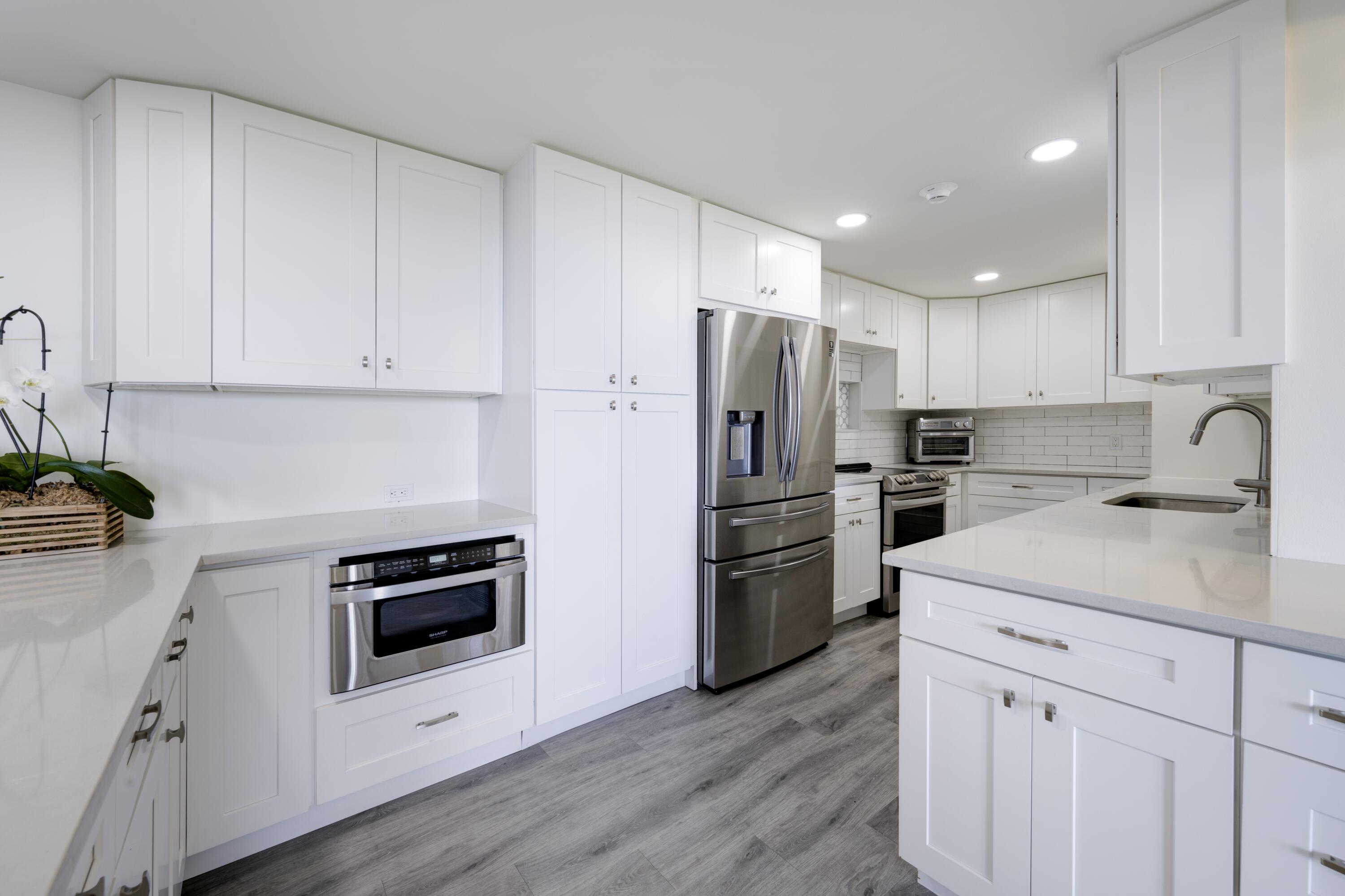 5600 North Flagler Drive, Unit 1207 West Palm Beach, FL 33407 - Photo 8 of 32 a kitchen with a refrigerator sink and white cabinets