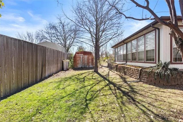 a view of a house with a large tree and wooden fence