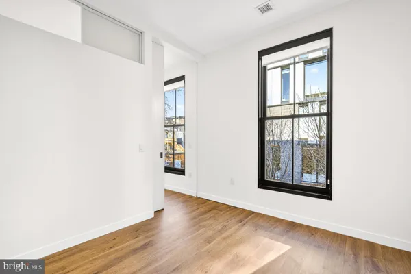 an empty room with wooden floor and windows