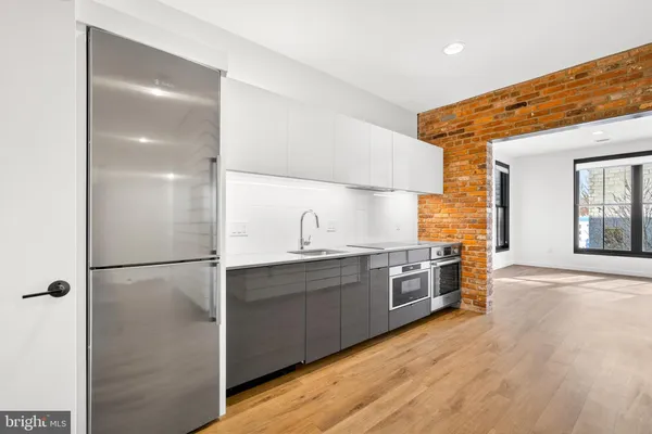 a kitchen with stainless steel appliances granite countertop a refrigerator a sink dishwasher a stove and white countertops with wooden floor