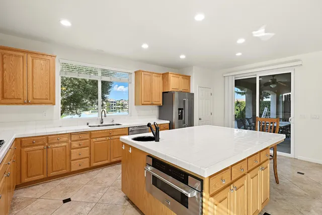 a kitchen with stainless steel appliances granite countertop a refrigerator a stove a sink a dining table and chairs with wooden floor