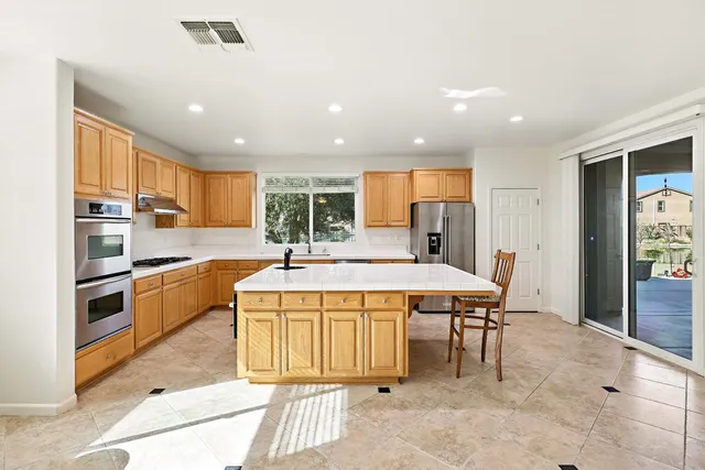 a large kitchen with kitchen island a large window in a dining table and chairs