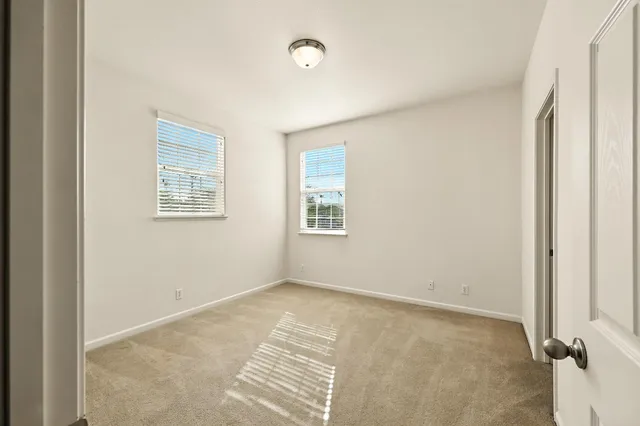 a view of an empty room with window and a ceiling fan