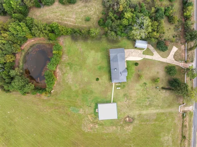 a aerial view of a house next to a yard with plants and large trees