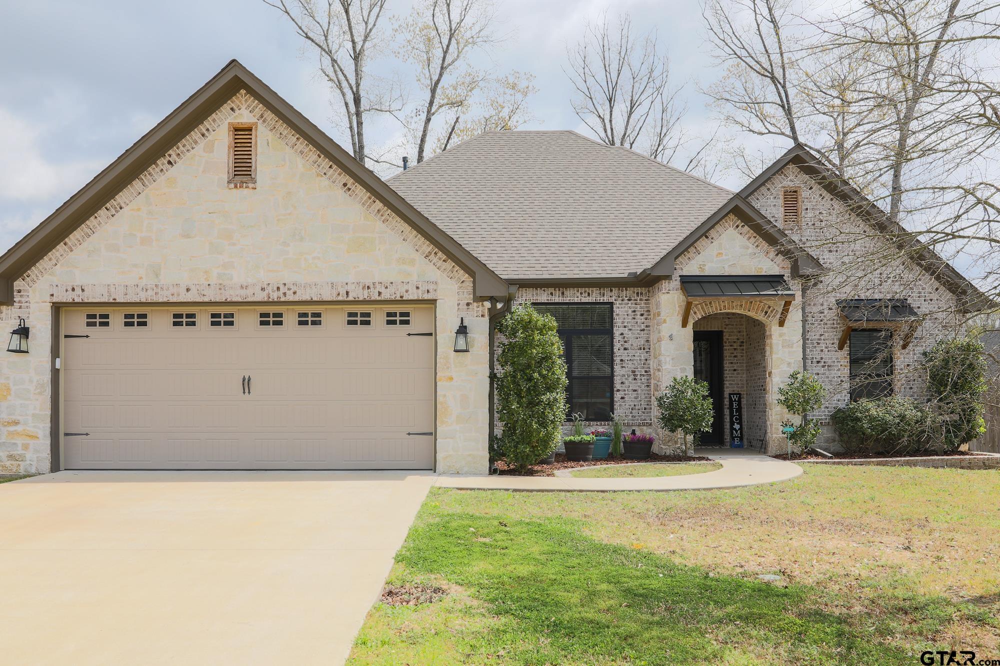 a view of a white house next to a yard with a large tree