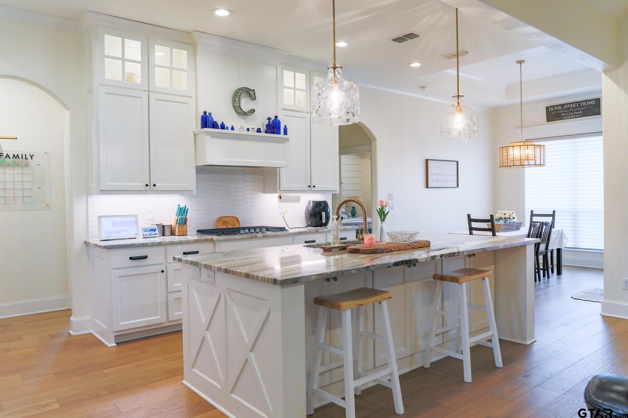 9065 Shallow Cove Tyler, TX 75703 - Photo 19 of 40 a kitchen with white cabinets and chairs