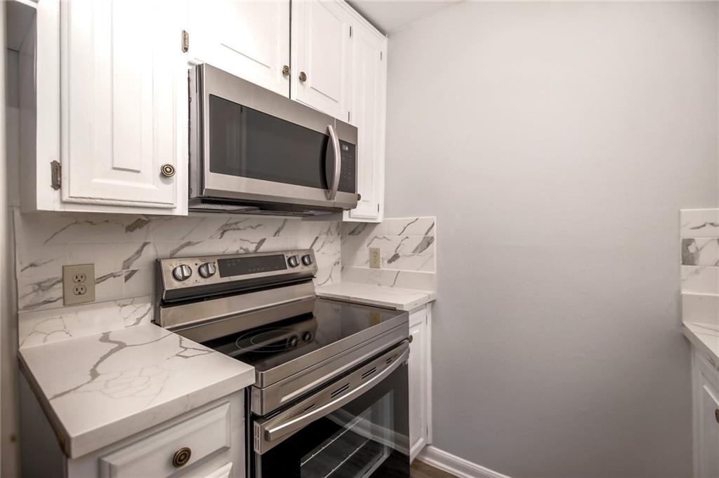 2529 Rio Grande Street, Unit 93 Austin, TX 78705 - Photo 14 of 19 Kitchen featuring white cabinetry, stainless steel appliances, and white countertops with grey veining