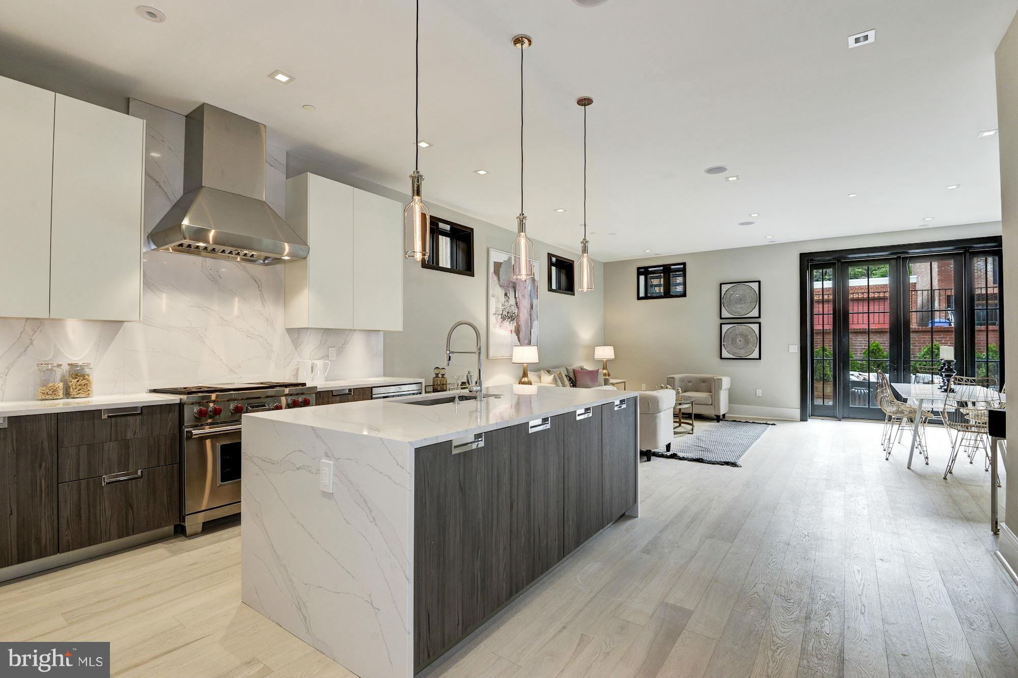 1310 Q Street Northwest, Unit 4 Washington, DC 20009 - Photo 4 of 16 a large kitchen with stainless steel appliances a stove a sink dishwasher a oven and a dining table with wooden floor