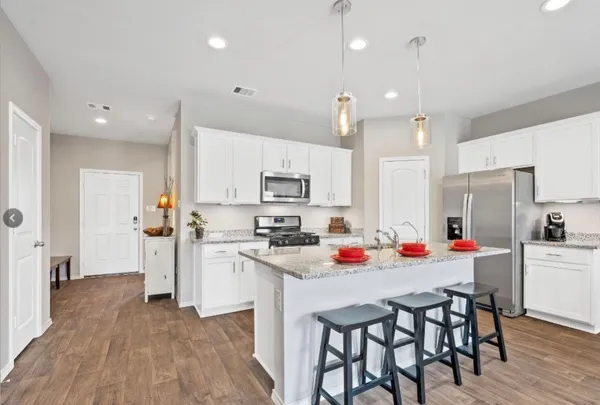 a kitchen with stainless steel appliances a white table and chairs in it